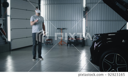 Mechanic inspecting a car in VR headset Mechanic inspecting a car in VR headset 92923165