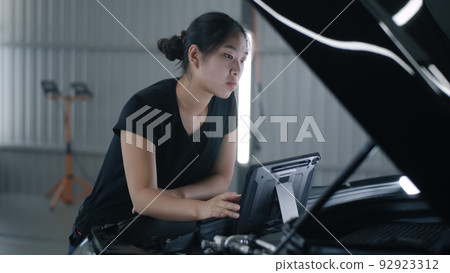 Female mechanic checking car with tablet 92923312