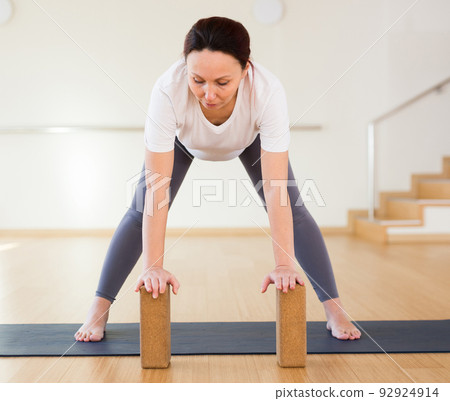 Pregnant woman is engaged in yoga. Standing Half Forward Bend or Ardha Uttanasana with blocks 92924914