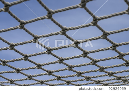 Knotted net against a blue sky. Knotted net against a blue sky. 92924969
