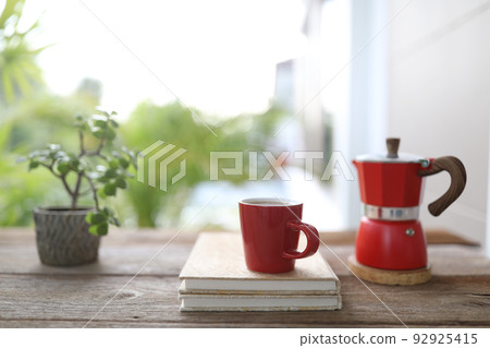 Red coffee and red moka pot and notebook on brown wooden table outdoor Red coffee and red moka pot and notebook on brown wooden table outdoor 92925415
