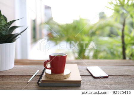 Red coffee and red phone and notebooks on brown wooden table outdoor Red coffee and red phone and notebooks on brown wooden table outdoor 92925416