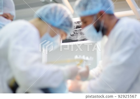 X-ray on the background of professional dentistry equipment and tools during a dental operation in hospital or clinic. Focus on x-ray. Modern technology of installation dental implants. X-ray on the background of professional dentistry equipment and tools during a dental operation in hospital or clinic. Focus on x-ray. Modern technology of installation dental implants. 92925567