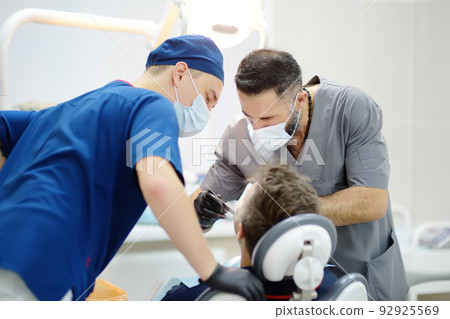 Dentists and patient at medical center. Doctor and intern doing check up a mature man teeth. Orthodontist and prosthetics appointment. 92925569