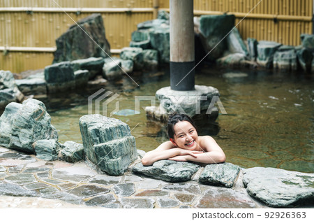 A young woman relaxing in a hot spring 92926363