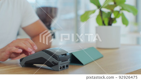 Close up in the cafe man makes coffee for a customer who pays by contactless mobile phone to credit card system in cafe with digital transaction service. 92926475