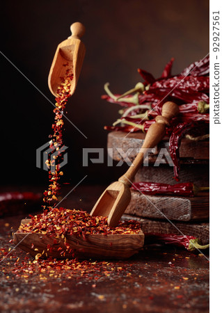 Chilli flakes are poured into a wooden dish. Chilli flakes are poured into a wooden dish. 92927561
