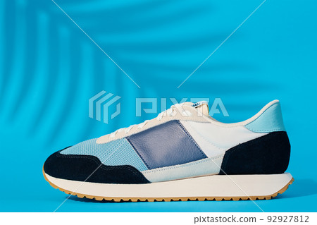 Stylish shoes on blue background with plant shadows, Trendy sneakers, Stylish fashionable minimalism concept 92927812