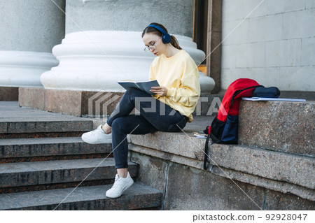 Positive daily affirmations for self love. Young woman in headphones writing in notebook 92928047