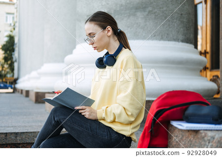 Positive daily affirmations for self love. Young woman in headphones writing in notebook 92928049