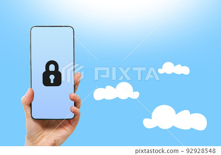 Cyberspace and online security. A female hand holds a smartphone with lock. Light blue background. Copy space. Cloud service and database concept Cyberspace and online security. A female hand holds a smartphone with lock. Light blue background. Copy space. Cloud service and database concept 92928548