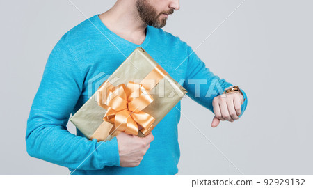 cropped man holding present or gift box and checking time on wristwatch, shopping time cropped man holding present or gift box and checking time on wristwatch, shopping time 92929132