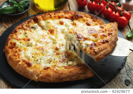 A slice of hot Italian pizza with stretching cheese. Pizza four cheeses with basil. 92929677