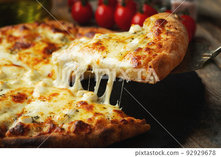 A slice of hot Italian pizza with stretching cheese. Pizza four cheeses with basil. 92929678