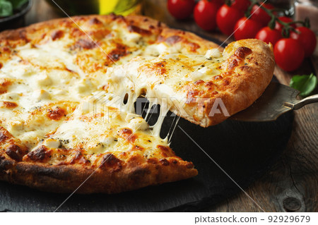 A slice of hot Italian pizza with stretching cheese. Pizza four cheeses with basil. 92929679