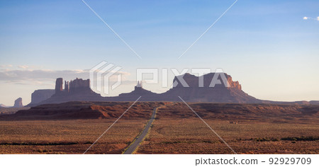 Scenic Road in the Dry Desert with Red Rocky Mountains in Background. 92929709