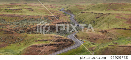 Scenic Road in the Countryside by green farm fields. 92929788