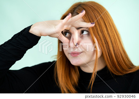 Funny pretty redhead girl showing bad smell sign with her fingers. 92930046