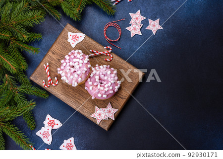 Pink glazed doughnut and marshmallow with Christmas decorations on a wooden cutting board 92930171