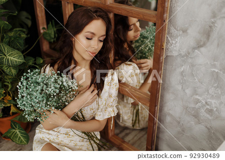 Beautiful girl in a dress sits on a chair 92930489