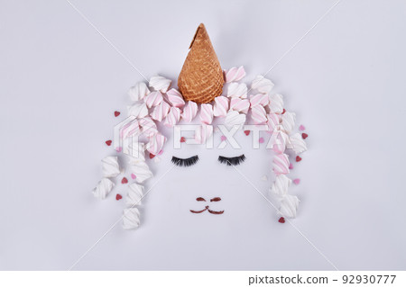 Ice cream cone and marshmallows represent hat and hair. Womans face with eyes closed. 92930777