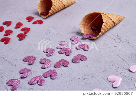 Close up purple sequin hearts from ice cream cone. Valentines day or creative concept. Close up purple sequin hearts from ice cream cone. Valentines day or creative concept. 92930807