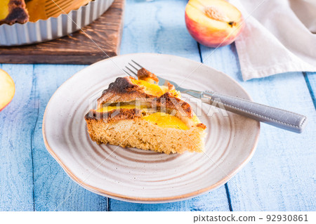 Fresh piece of peach pie and fork on a plate on the table. Homemade pastries 92930861