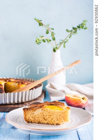 A piece of peach pie on a plate on the table. Homemade pastries. Vertical view 92930862
