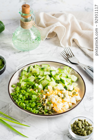 Fresh salad of cucumber, boiled egg and green onion on a plate. Ketogenic diet. Vertical view Fresh salad of cucumber, boiled egg and green onion on a plate. Ketogenic diet. Vertical view 92931117