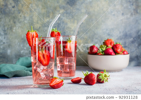 Refreshing cocktail with strawberries in glasses with a straw on the table and a bowl with berries. Refreshing cocktail with strawberries in glasses with a straw on the table and a bowl with berries. 92931128