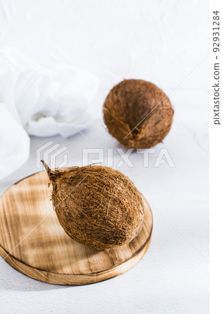 Two whole ripe coconuts on the table. Tropical fruits. Vertical view 92931284