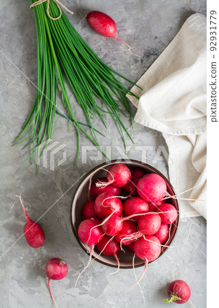 Fresh whole radish in a bowl and a bunch of green onions on the table. Top and vertical view 92931779