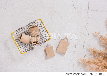 Craft paper bags for shopping in the basket and next to it on a concrete background. Top view. 92931882