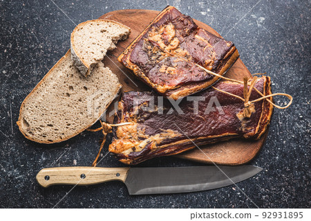 Whole smoked bacon on cutting board. 92931895