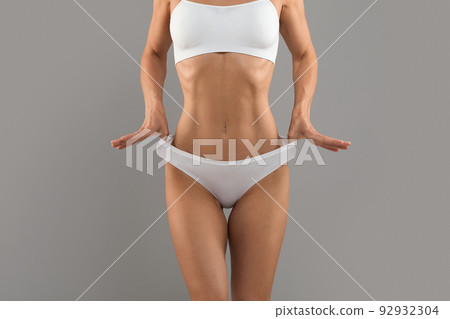 Unrecognizable fit woman with slim body in underwear pulling up white panties Unrecognizable fit woman with slim body in underwear pulling up white panties 92932304