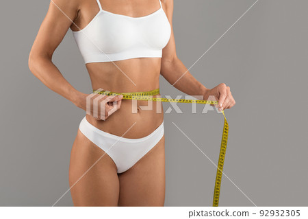 Weight Loss. Slim Young Woman In Underwear Measuring Waist With Yellow Tape Weight Loss. Slim Young Woman In Underwear Measuring Waist With Yellow Tape 92932305