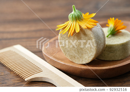Natural organic calendula solid shampoo pieces, calendula flower and wooden comb. Selective focus. 92932516