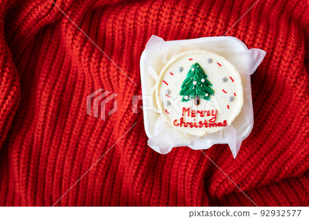 Christmas cake with the inscription merry christmas, decorated with icing, on a red background, top view. 92932577