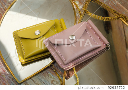 Beautiful modern women's leather wallets lying on mirrors on a sunny day 92932722