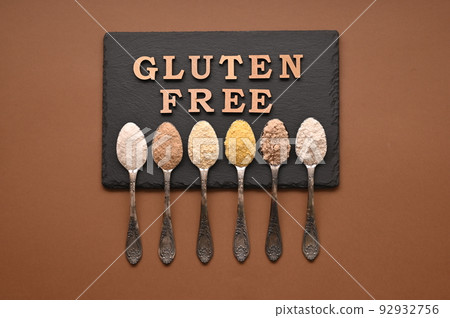 Gluten free text and spoons of various gluten free flour, almond, buckwheat, rice, corn, oat, chickpea. Flat lay, top 92932756