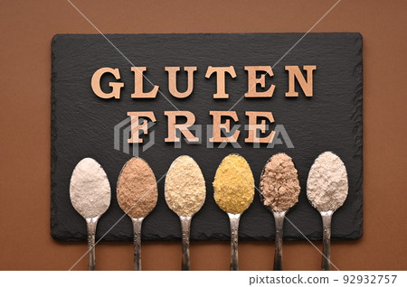 Gluten free text and spoons of various gluten free flour, almond, buckwheat, rice, corn, oat, chickpea. Flat lay, top 92932757