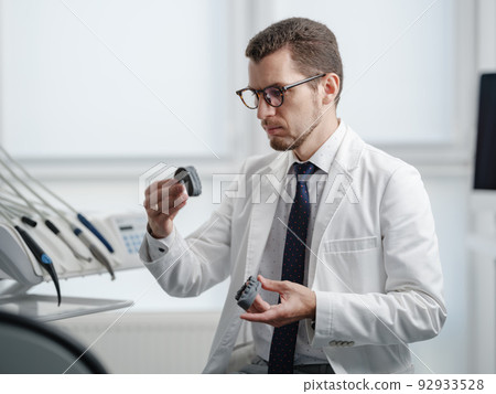 Dentist looking at photopolymer jaw printed on a 3d printer. 92933528