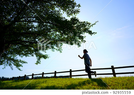 Silhouette of a woman walking (running) on the bank under the blue sky 92935559