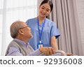 Asian nurse holding an elderly man with a walking stick for physiotherapy. 92936008