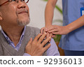 Close up hand of hands of nursing aide holding and patting winkled hand of a patient.Domiciliary care for sick elderly. 92936013