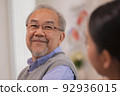 Happiness Cheerful elderly men talking with female caregiver nurse doctor having health checking consult at home. 92936015