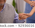Close up hand of hands of nursing aide holding and patting winkled hand of a patient.Domiciliary care for sick elderly. 92936016