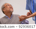 Close up hand of hands of nursing aide holding and patting winkled hand of a patient.Domiciliary care for sick elderly. 92936017