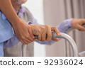 Close up.Asian nurse holding an elderly man with a walking stick for physiotherapy. 92936024