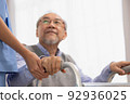 Close up.Asian nurse holding an elderly man with a walking stick for physiotherapy. 92936025